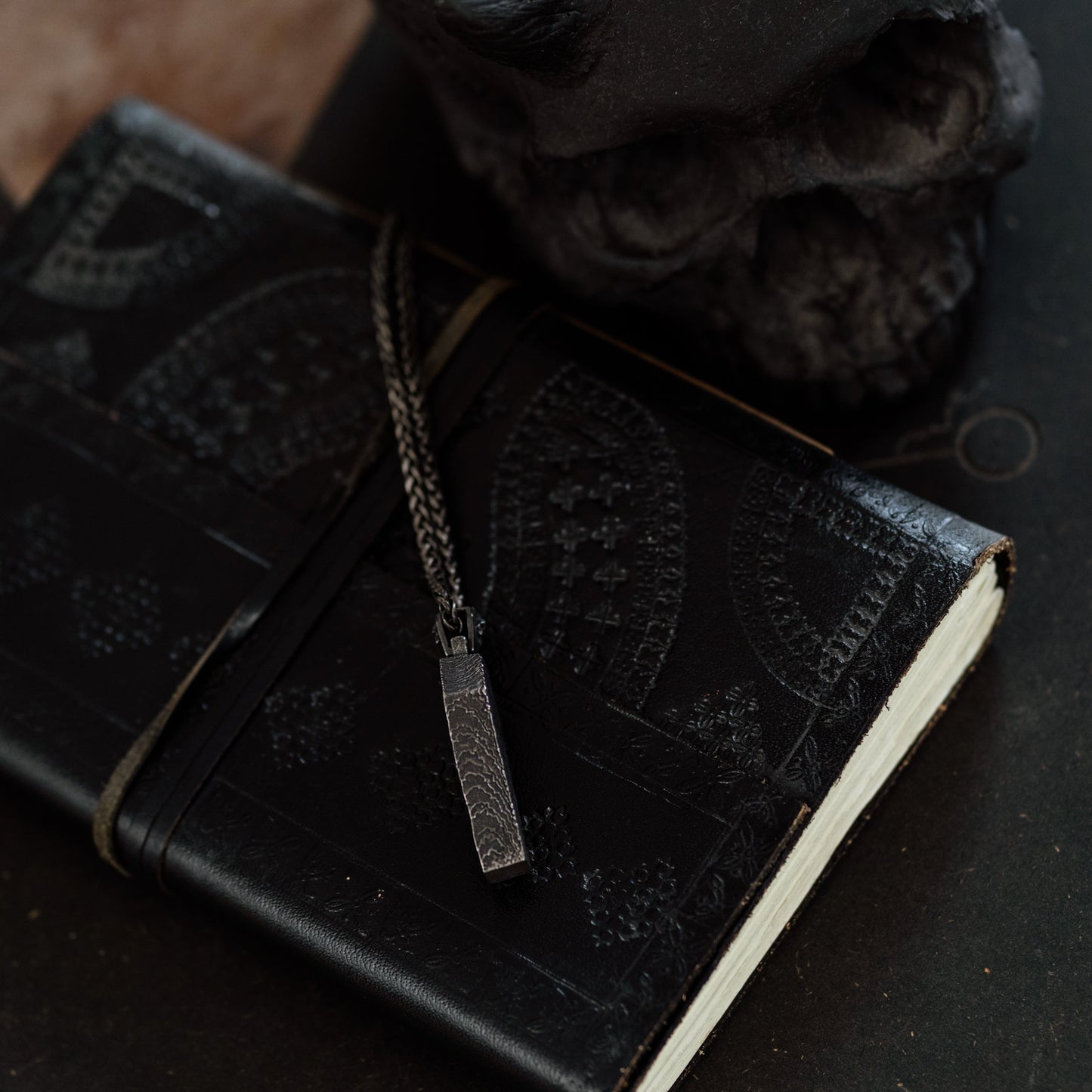 Black leather notebook with decorative stitching on a dark surface