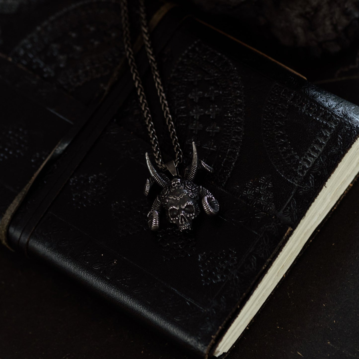 Black leather-bound book with a necklace on a dark surface