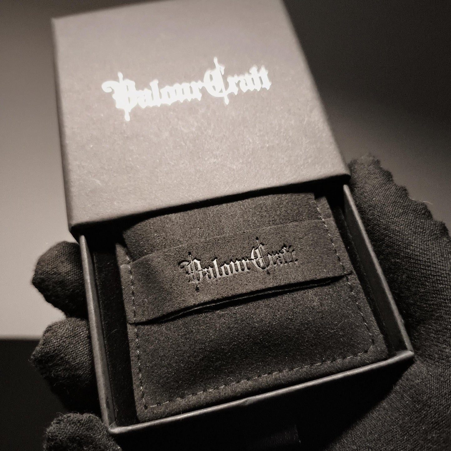 Black leather cardholder with 'Valour Craft' branding in a box held by a gloved hand.