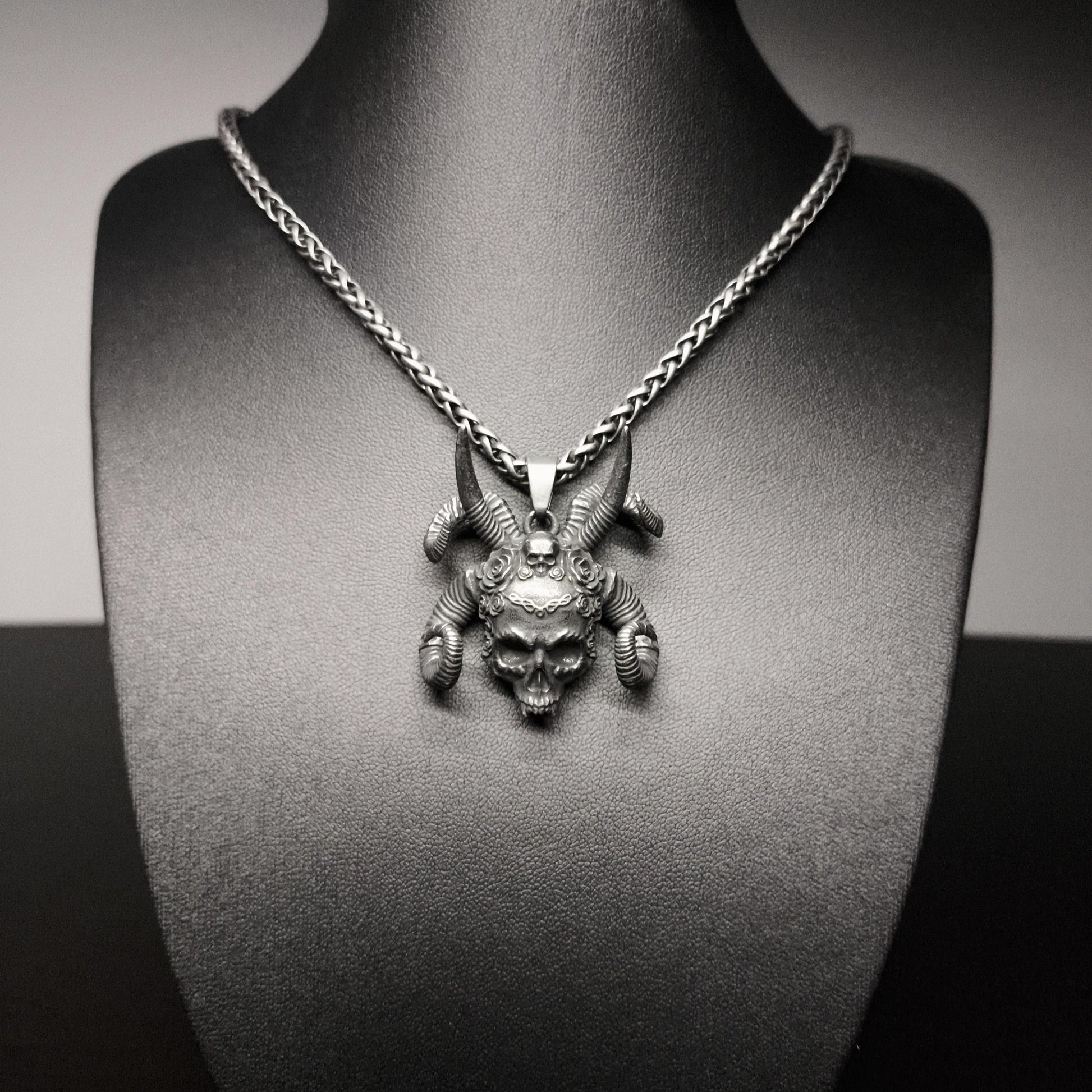 Silver necklace with a detailed pendant on a black mannequin bust.