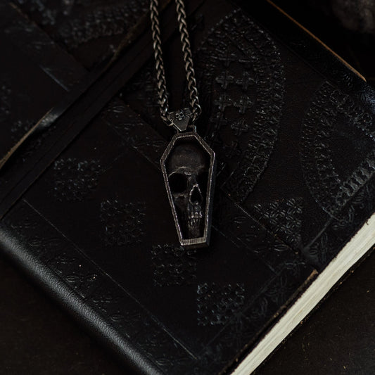 Black coffin-shaped pendant necklace on a black notebook