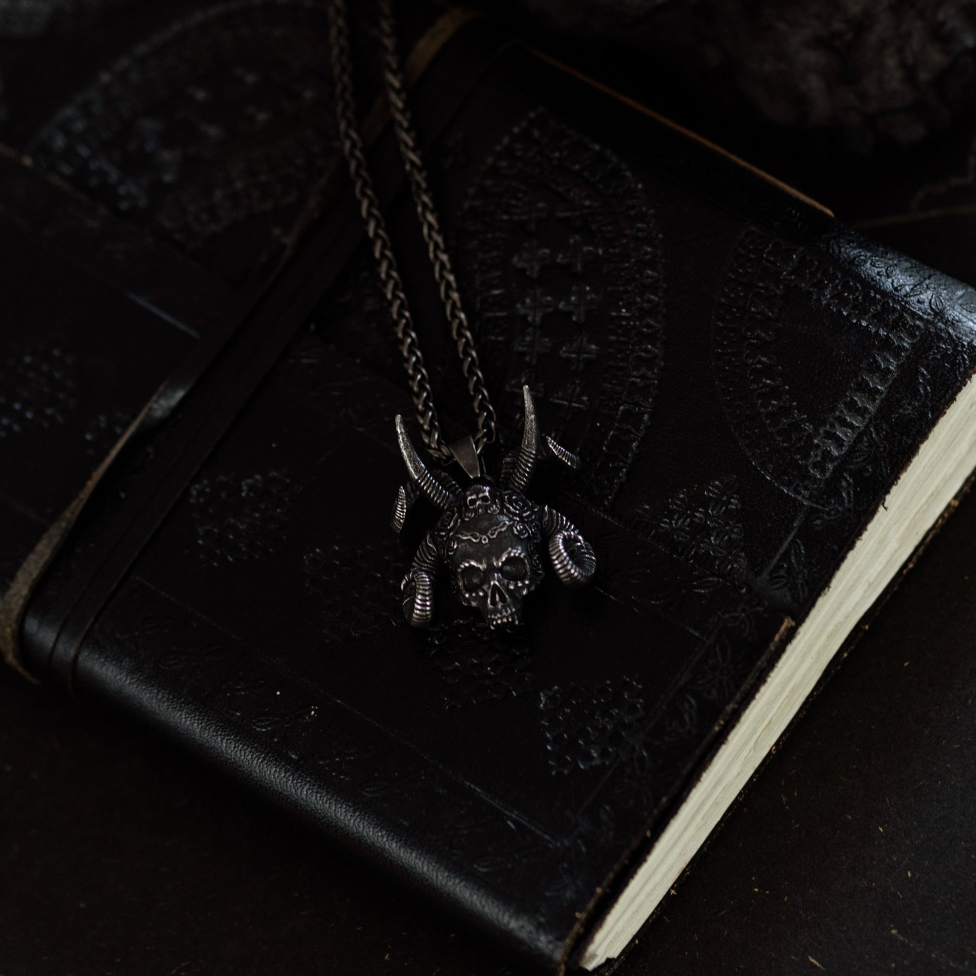 Black leather-bound book with a necklace on a dark surface