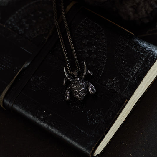 Black leather-bound book with a necklace on a dark surface