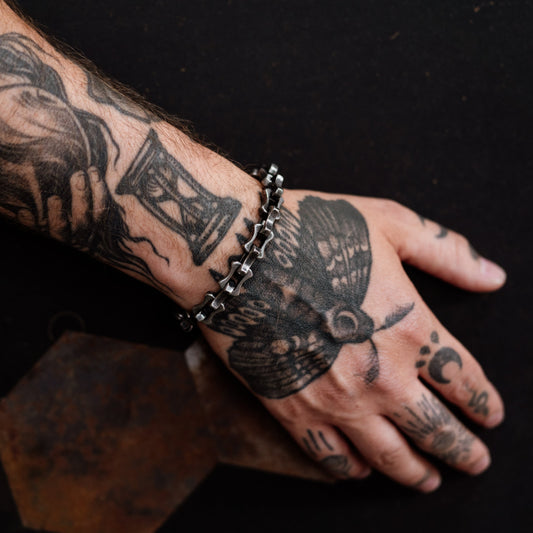 Hand with tattoos and a bracelet on a dark background